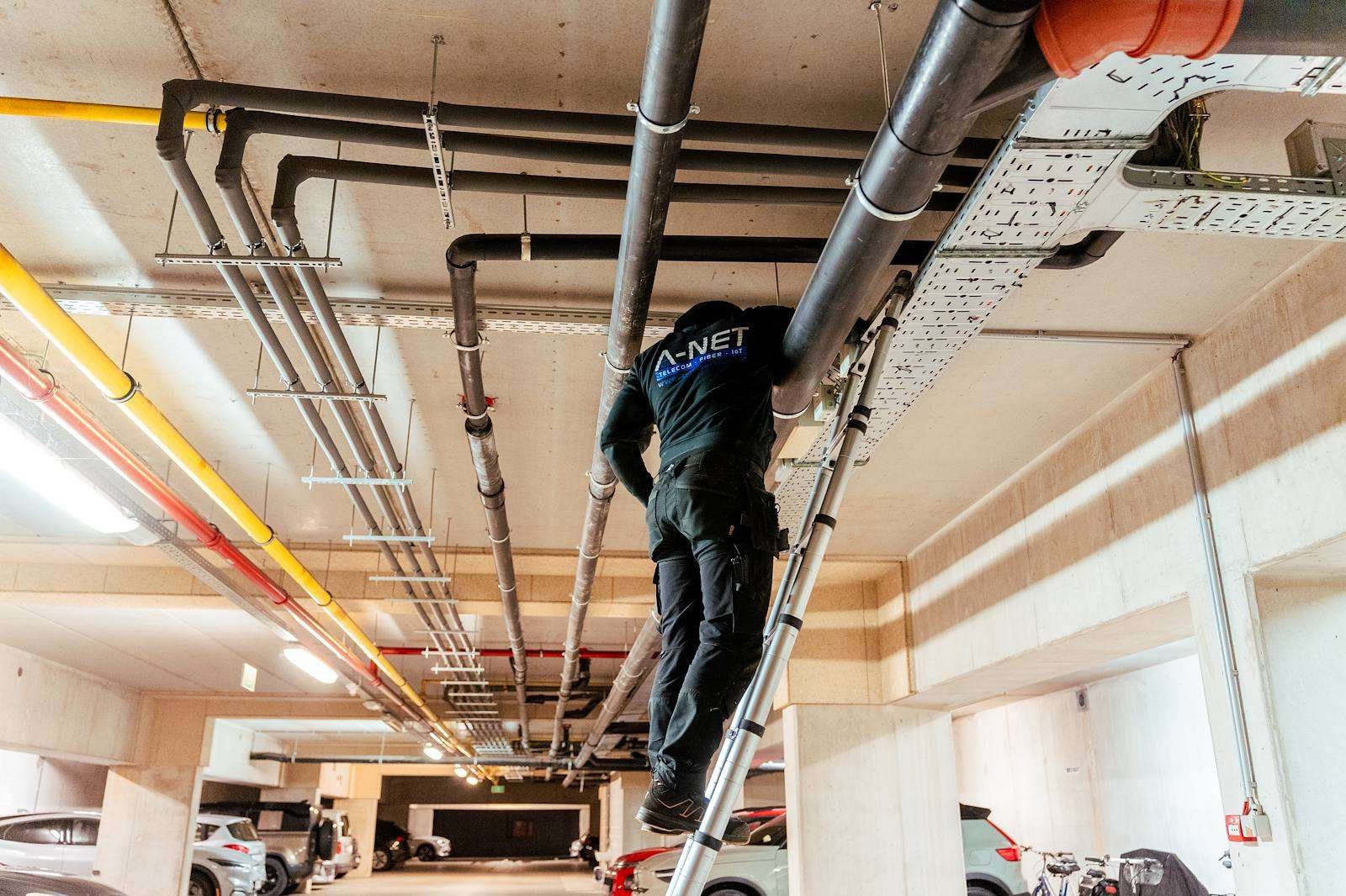 Technicus van A-NET werkt aan de kabelgoten in een parkeergarage