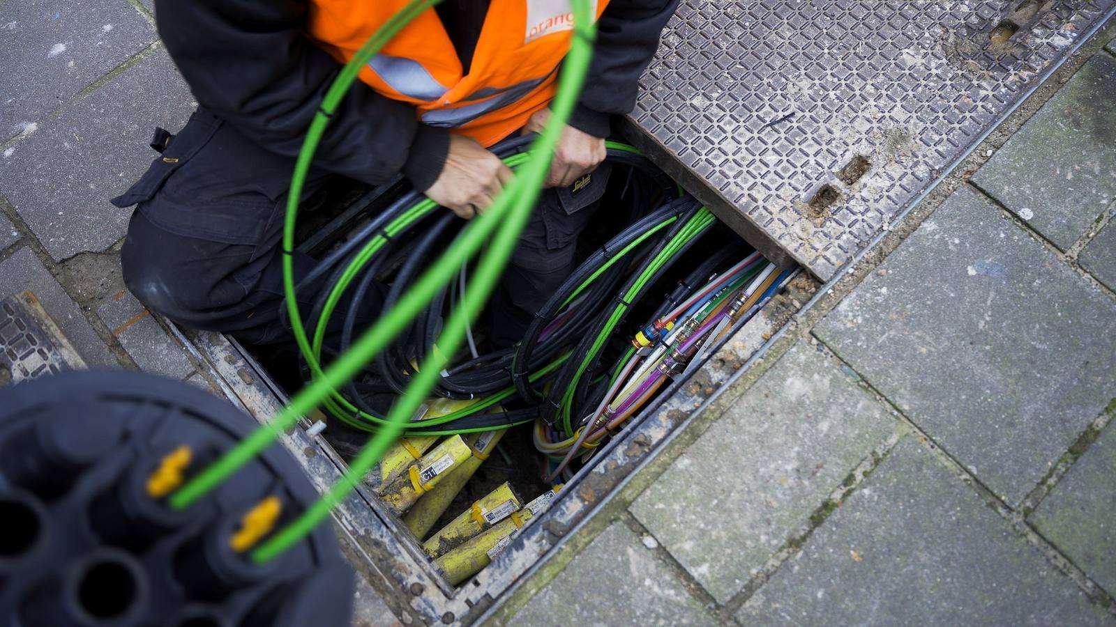 Technicus van A-NET werkt aan glasvezelkabels in een straatput