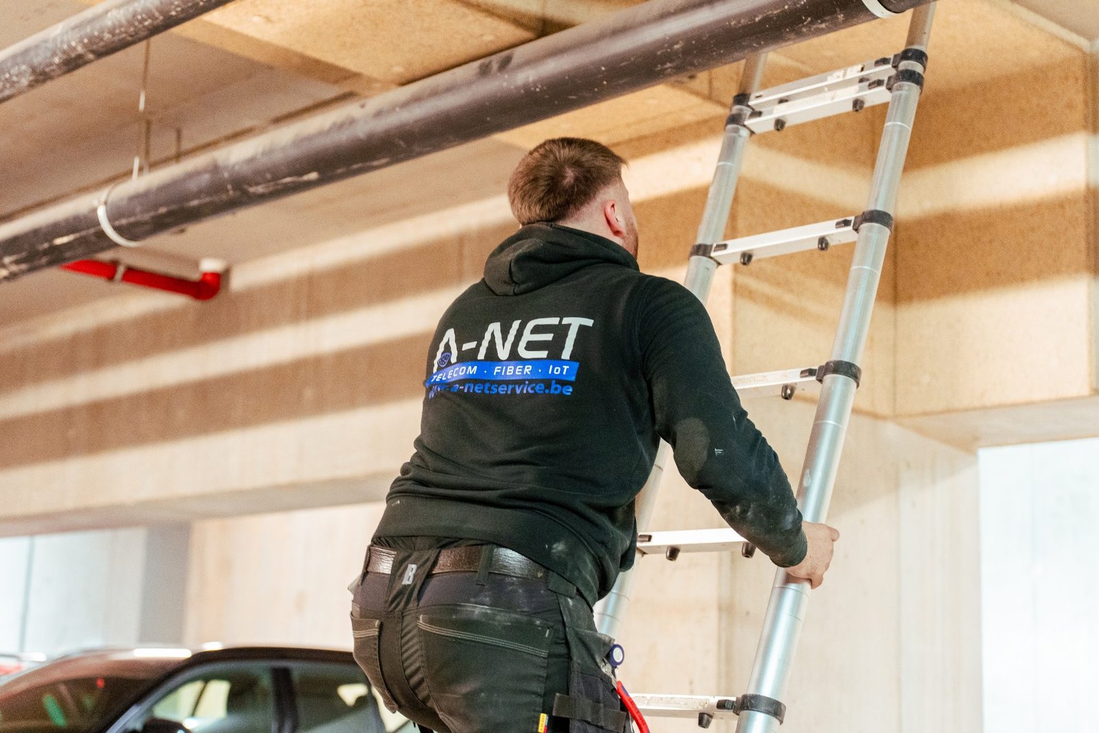 Technicus van A-NET installeert een kabelgoot in een parkeergarage